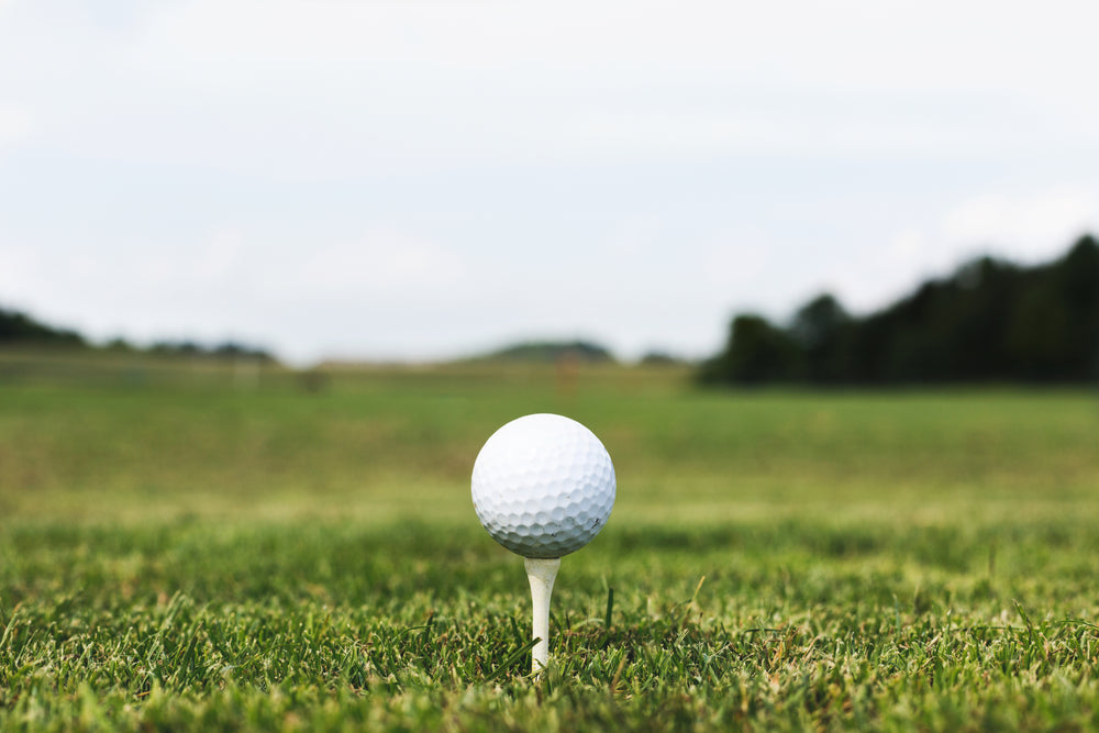A white golf ball on a tee in close-cut grass